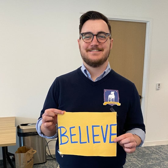 Employee holding believe sign